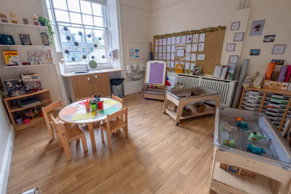 Bright and welcoming Thrive Childcare room featuring educational toys, arts and crafts supplies, a cosy reading corner, and outdoor play area for nurturing children's development and learning.
