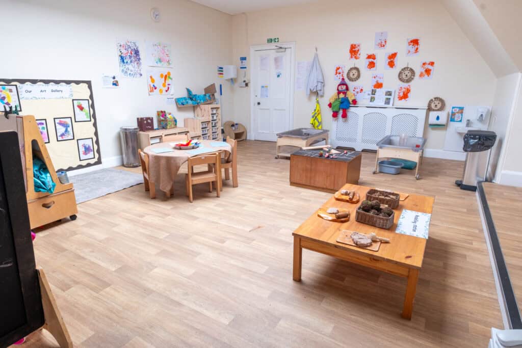 Bright indoor childcare classroom at Thrive Childcare with art displays, toys, and activity tables designed for early childhood development and learning.