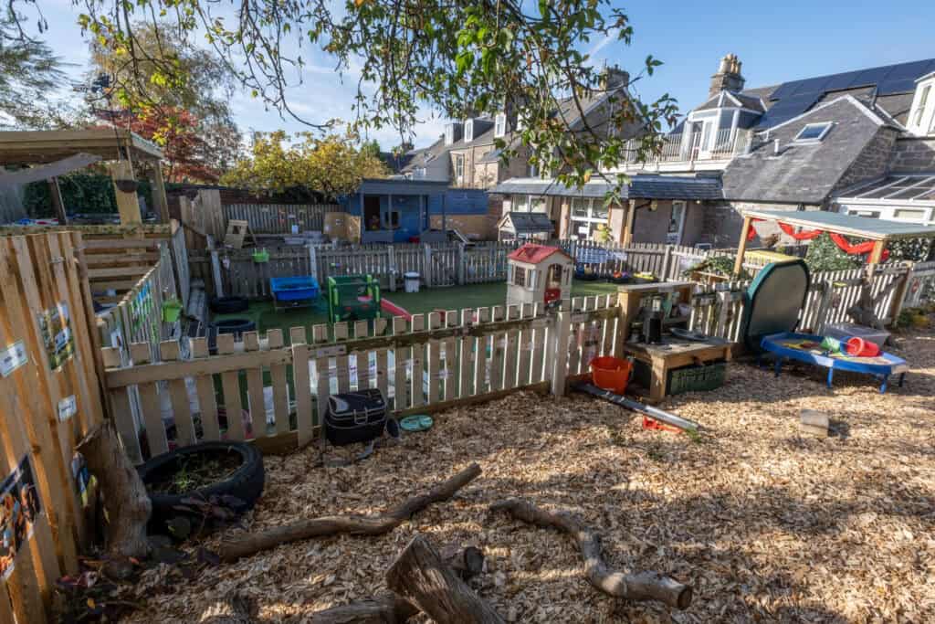 Bright outdoor childcare play area with toys, sandpit, and lush trees, providing a safe environment for young children to learn and play at Thrive Childcare.