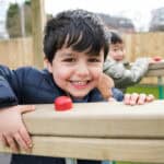 Happy young boy smiling outdoors at Thrive Childcare, enjoying outdoor play in a secure childcare environment in the UK.
