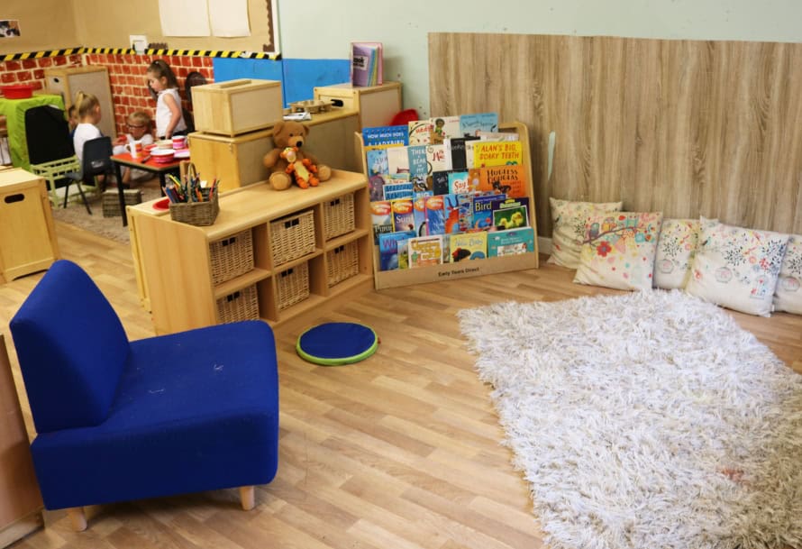 Bright indoor reading and play area at Thrive Childcare with cozy seating, children's books, and soft rug, fostering a nurturing environment for early childhood development and learning.