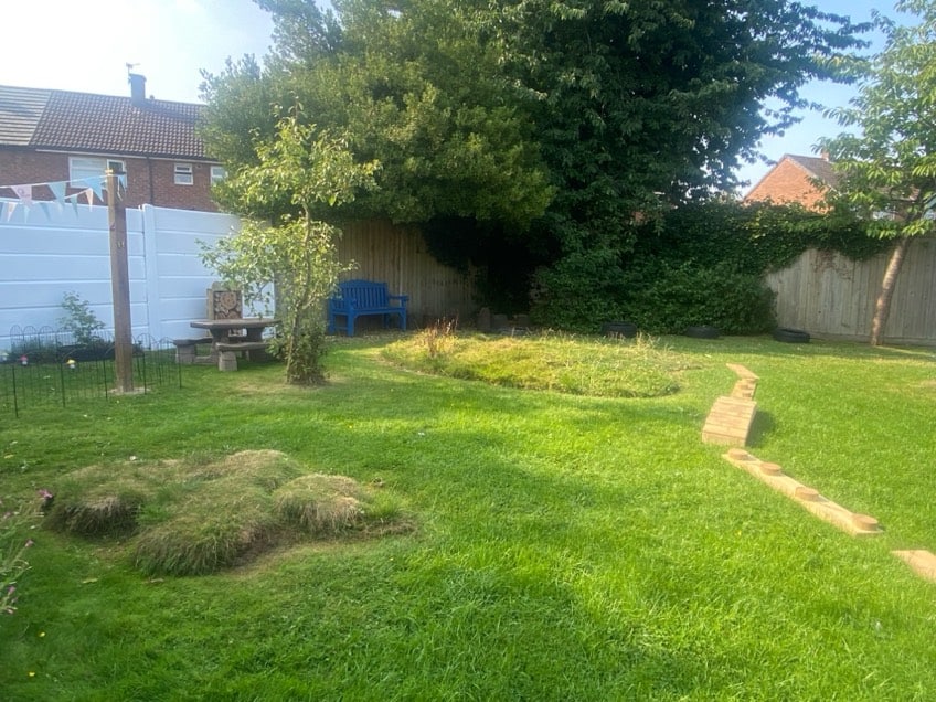 Playground at Holyrood Nursery Swinton with grassy areas, a small hill, and a paved path, providing a safe outdoor space for children to play and explore at Thrive Childcare.