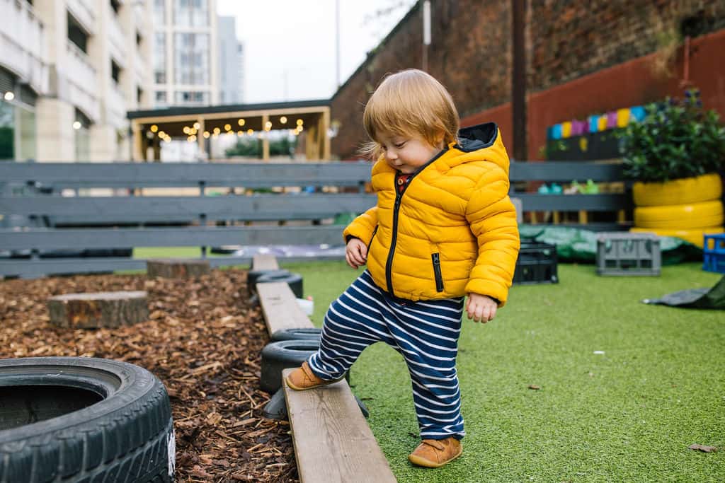 Bright young child exploring outdoor play area at Thrive Childcare, engaging with nature and sensory activities to promote early childhood development and learning.