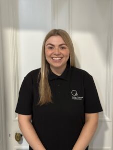 Compassionate childcare staff member smiling, wearing Thrive Childcare branded polo shirt, dedicated to early childhood education in a welcoming environment, nurturing young children's development.