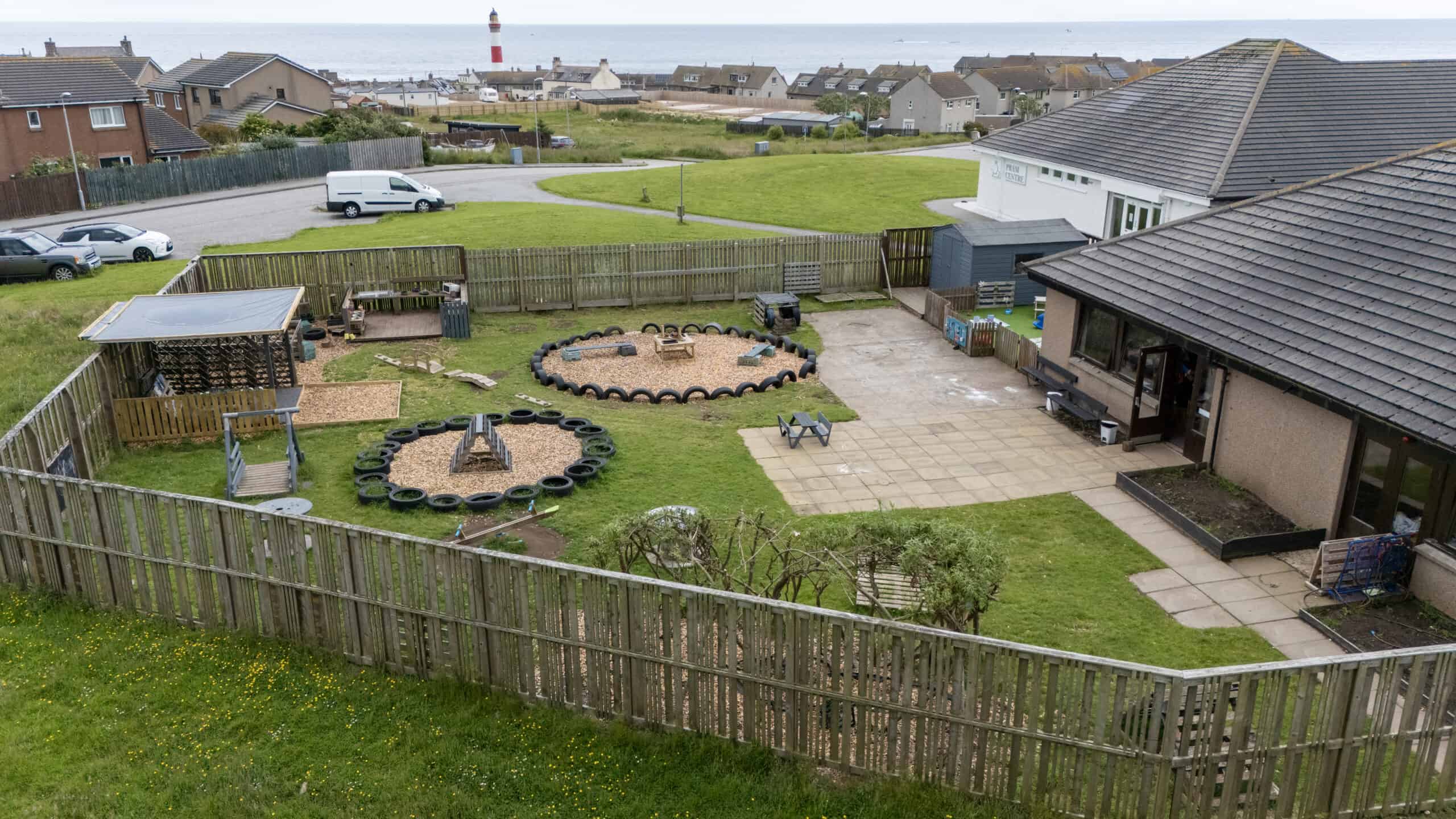 Bright outdoor play area at Thrive Childcare with sandpits, tire obstacle courses, and climbing structures in a secure, fenced yard near the coast, offering a safe, engaging environment for children's outdoor activities.