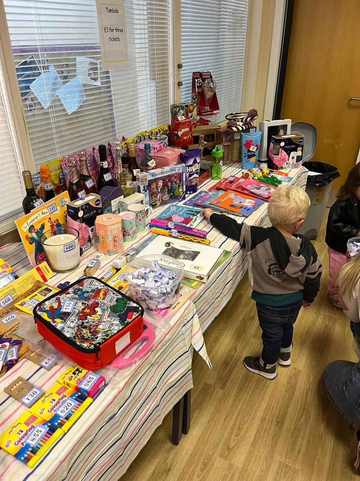 Bright indoor children's charity sale with toys, books, and gifts at Thrive Childcare, promoting community engagement and support for childcare services and early childhood development.