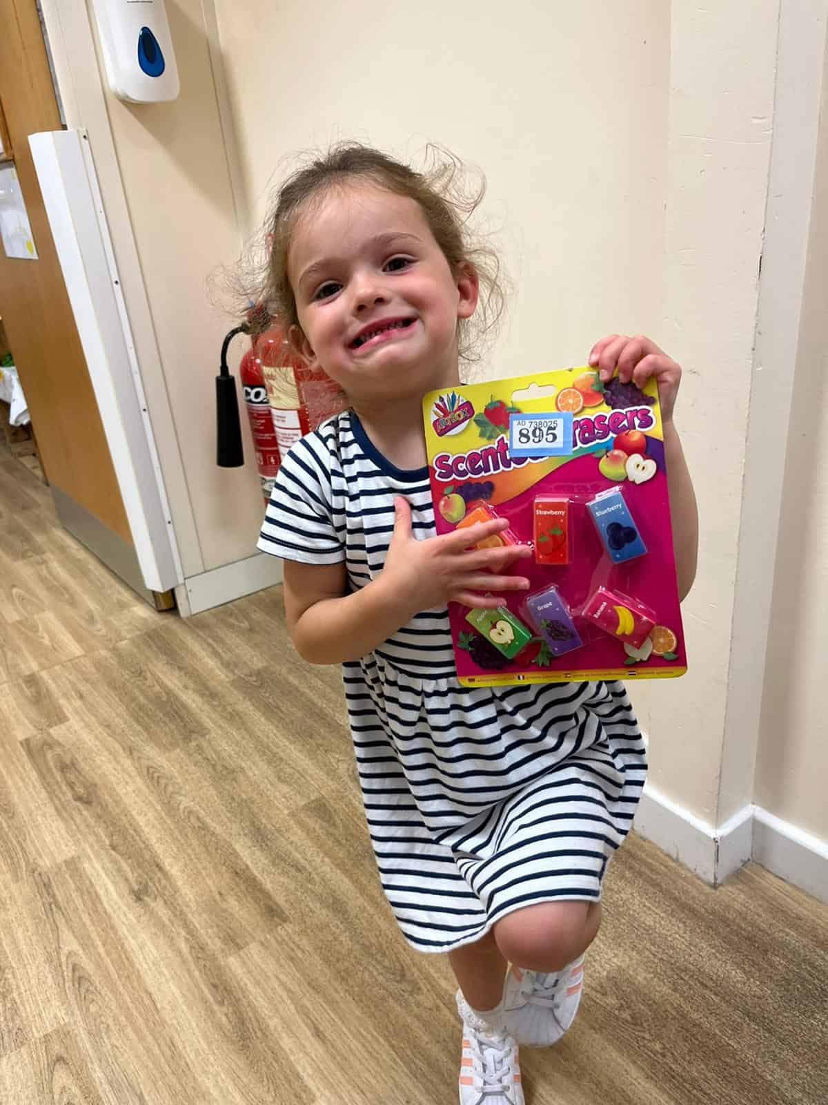 Bright young girl holding toy scent erasers at Thrive Childcare, showcasing a fun and engaging environment for children’s development and learning.