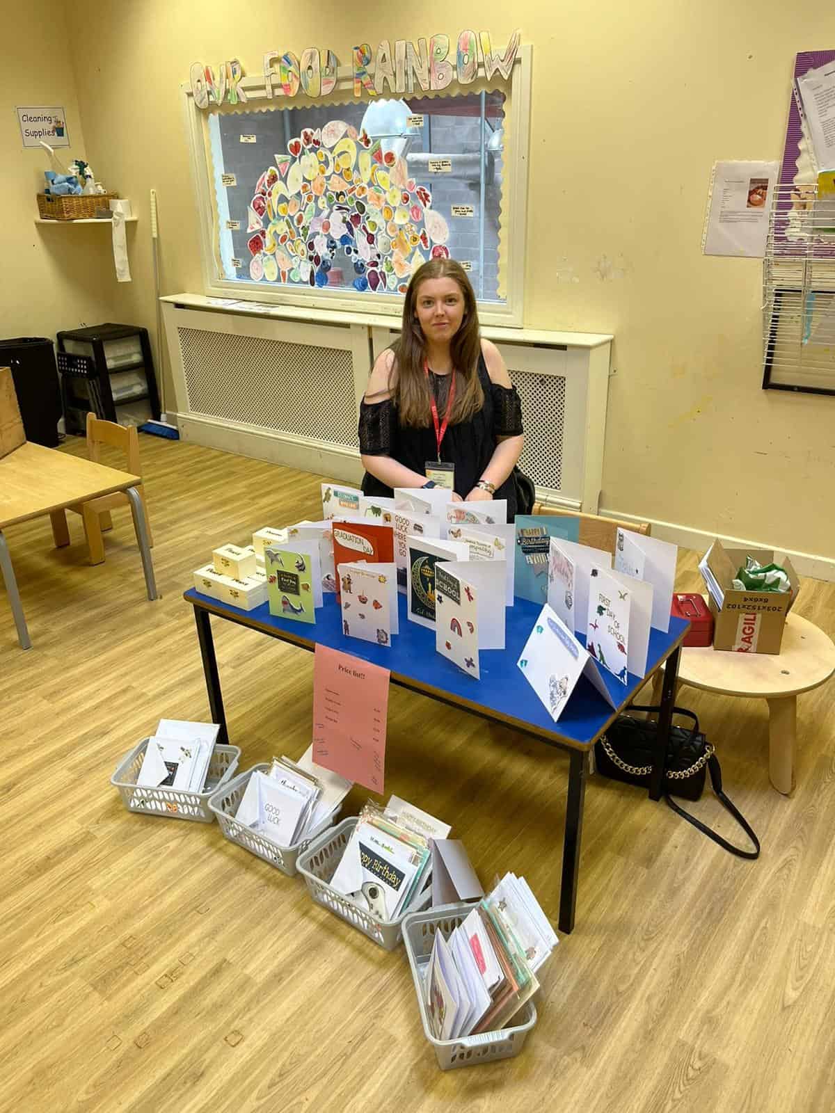Bright cheerful childcare environment at Thrive Childcare, showcasing a friendly staff member promoting early childhood education, reading resources, and engaging activities for children's development.