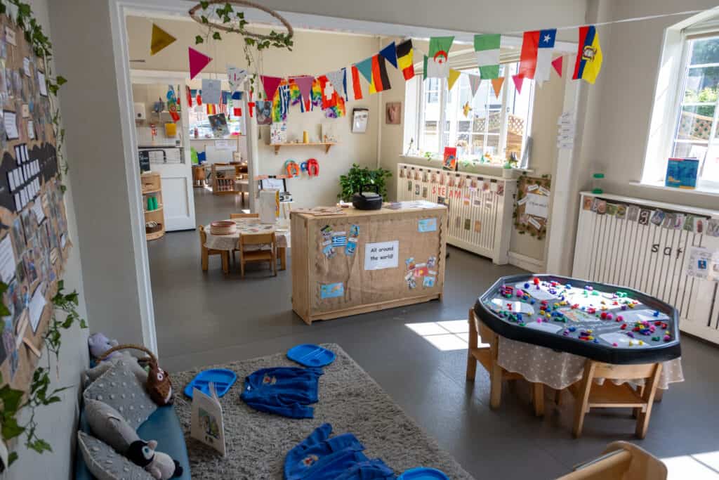 Bright indoor childcare playroom at Thrive Childcare with educational toys, flags from around the world, and child-sized furniture, promoting a fun and inclusive learning environment for young children.