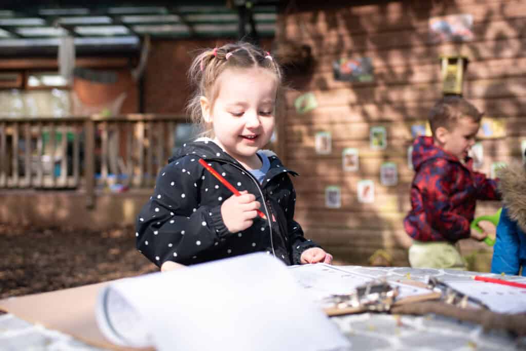1. Young girl engaging in outdoor art activities at Thrive Childcare, fostering creativity and imaginative play for early childhood development.