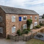 Bright brick-built Thrive Childcare centre with secure outdoor play area, surrounded by greenery and fencing, offering a safe environment for children's early learning and development.