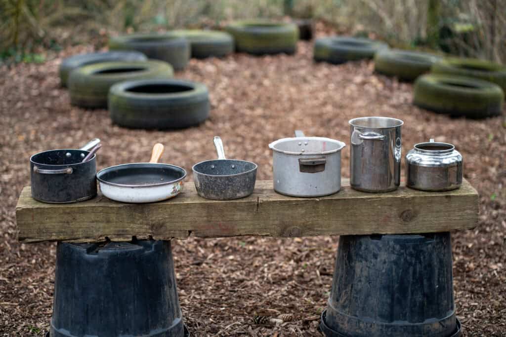 Outdoor play area at Thrive Grosvenor House with tires and containers for children's activities. Safe, engaging environment for early childhood development.