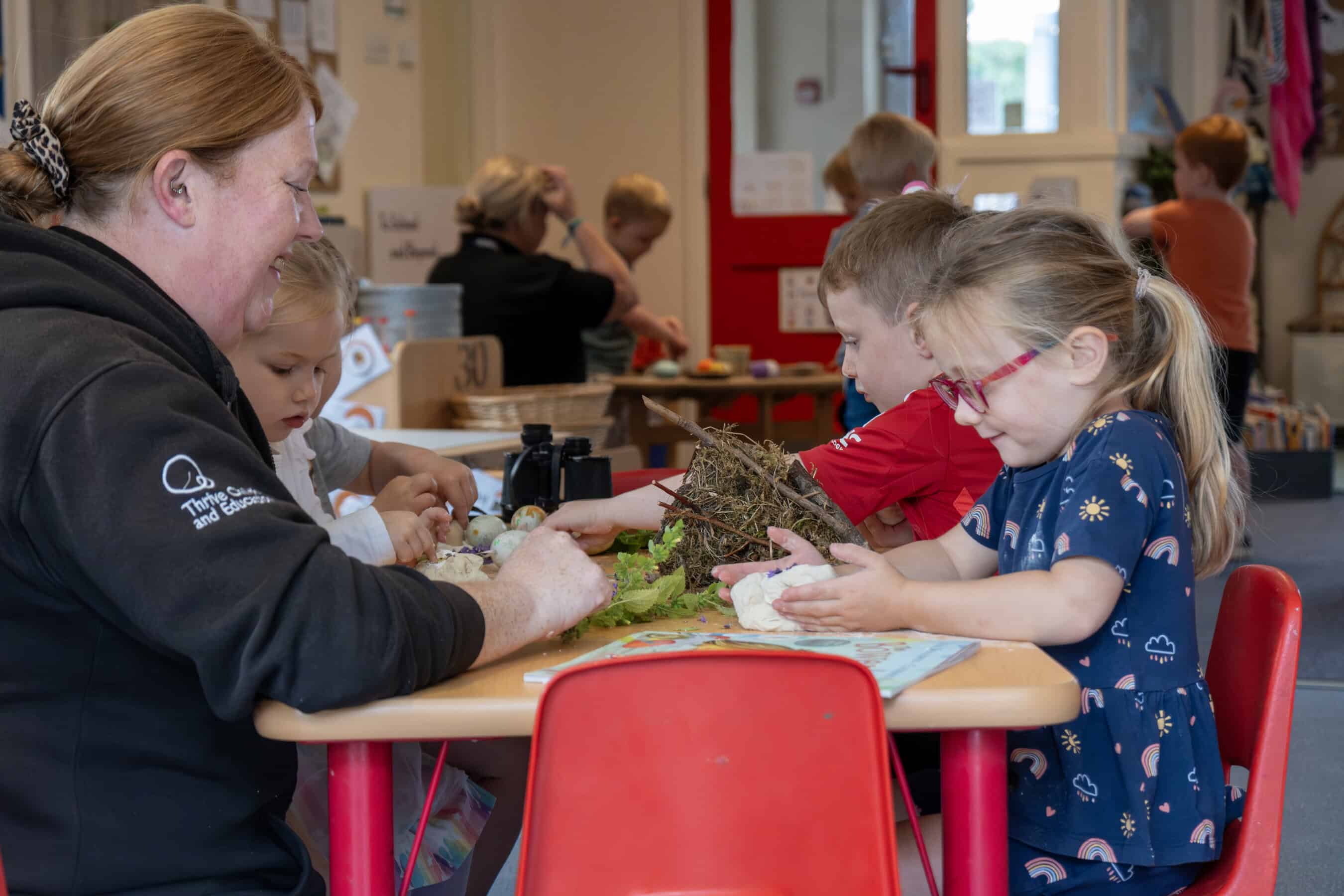 1. Children engaging in creative arts and crafts activities at Thrive Childcare with attentive educators in a nurturing learning environment.