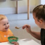 Bright toddler receives nutritious meal at Thrive Childcare, where caring staff promote healthy eating habits.