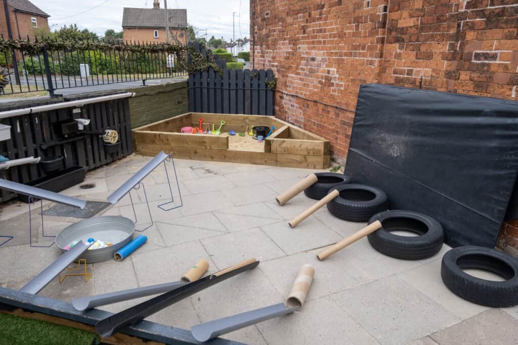 1. Bright outdoor toddler play area at Thrive Childcare with tires, sandpit, and sensory toys for early childhood development.