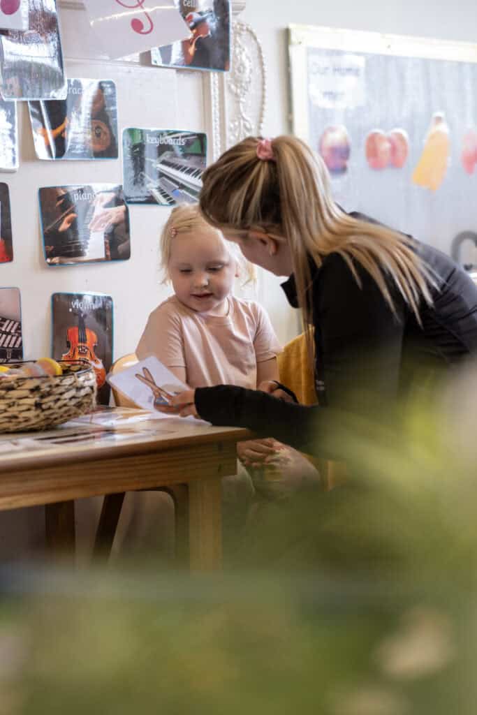 Bright young girl and caring adult engaging in educational activity at Thrive Childcare, promoting early childhood development and learning through play.
