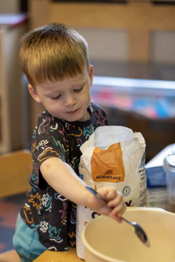 1. Young boy baking with flour at Thrive Childcare, demonstrating early childhood development and learning activities.