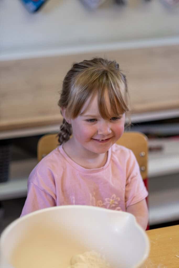 Bright-eyed young girl smiling at Thrive Childcare, engaging in fun and educational activities in a nurturing environment tailored for early childhood development.