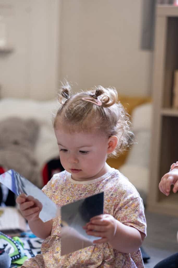 1. Adorable young girl with curly blonde hair in pigtails, exploring photos at Thrive Childcare, highlighting early childhood learning and enrichment activities.