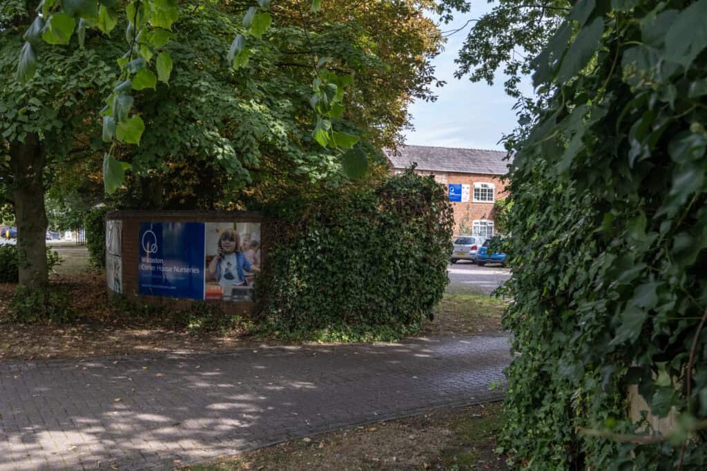 Bright nursery centre signboard at Thrive Childcare Wistaston surrounded by lush green trees and bushes, inviting for parents seeking quality nursery education and childcare services in the local community.