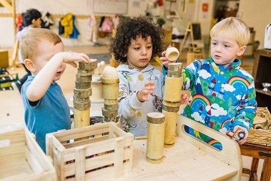 Colourful children playing with wooden blocks and toys in a vibrant preschool classroom at Thrive Childcare, promoting early childhood development and hands-on learning.