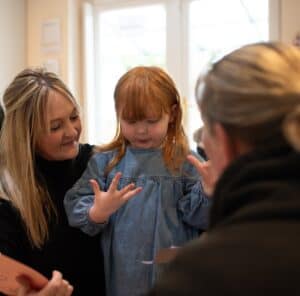 Cheerful young girl engaging with caregivers at Thrive Childcare, fostering early childhood development in a safe and nurturing environment.