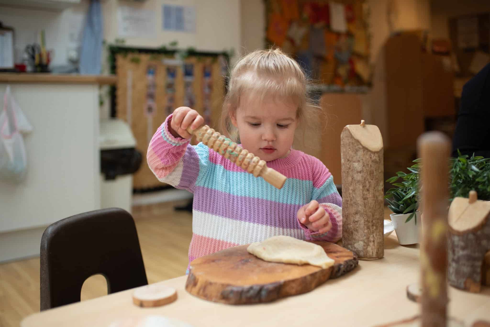 1. Young girl at Thrive Childcare engaging in creative play with wooden tools and natural materials in a nurturing early learning environment.
