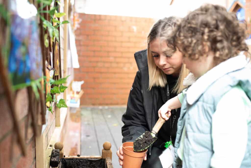 1. Happy female caretaker and young child planting in outdoor garden, fostering early childhood education, nurturing nature skills, and promoting growth at Thrive Childcare.