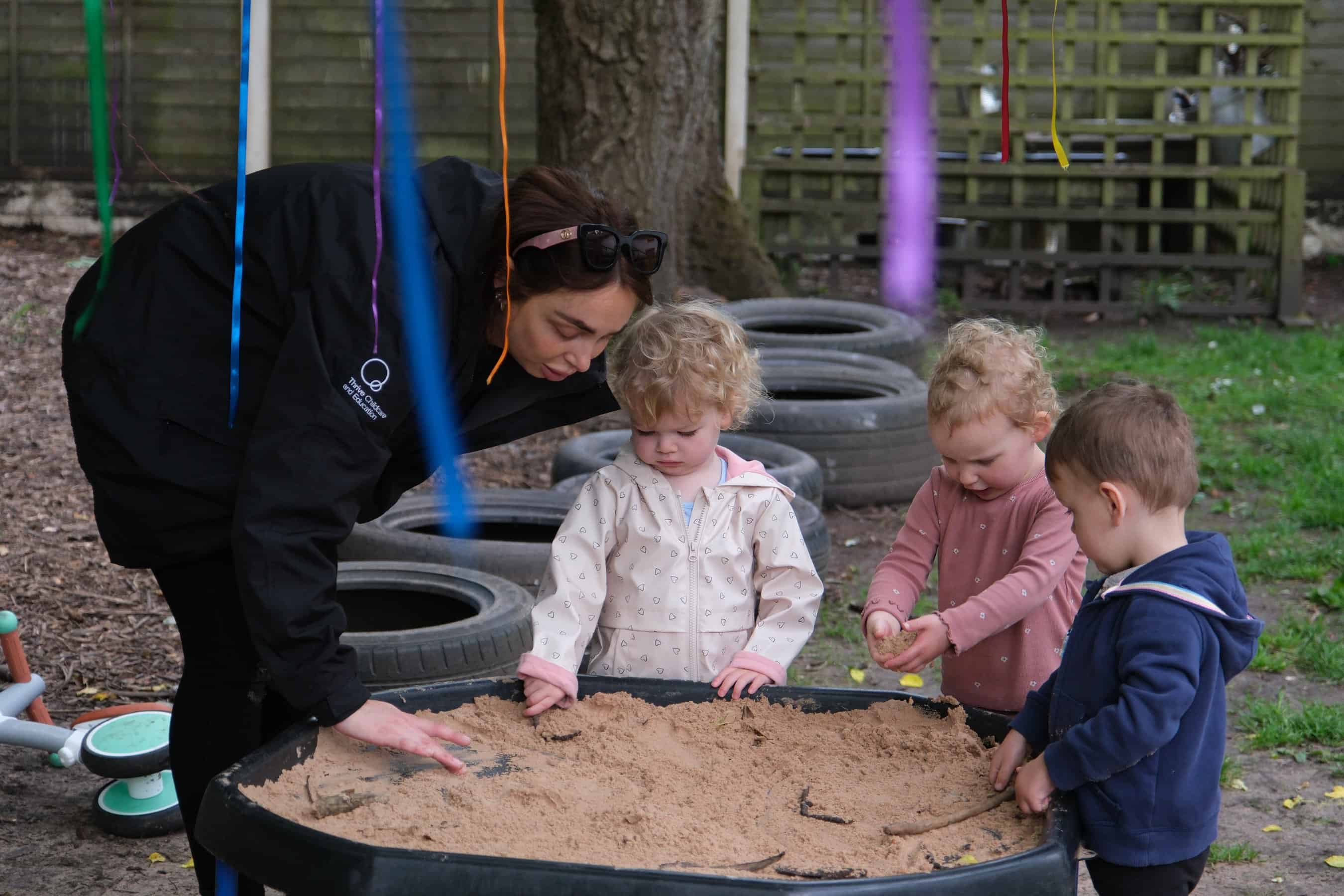 Outdoor childcare activity with young children and caregiver engaging in sensory play at Thrive Childcare, promoting early childhood development and outdoor learning experiences.