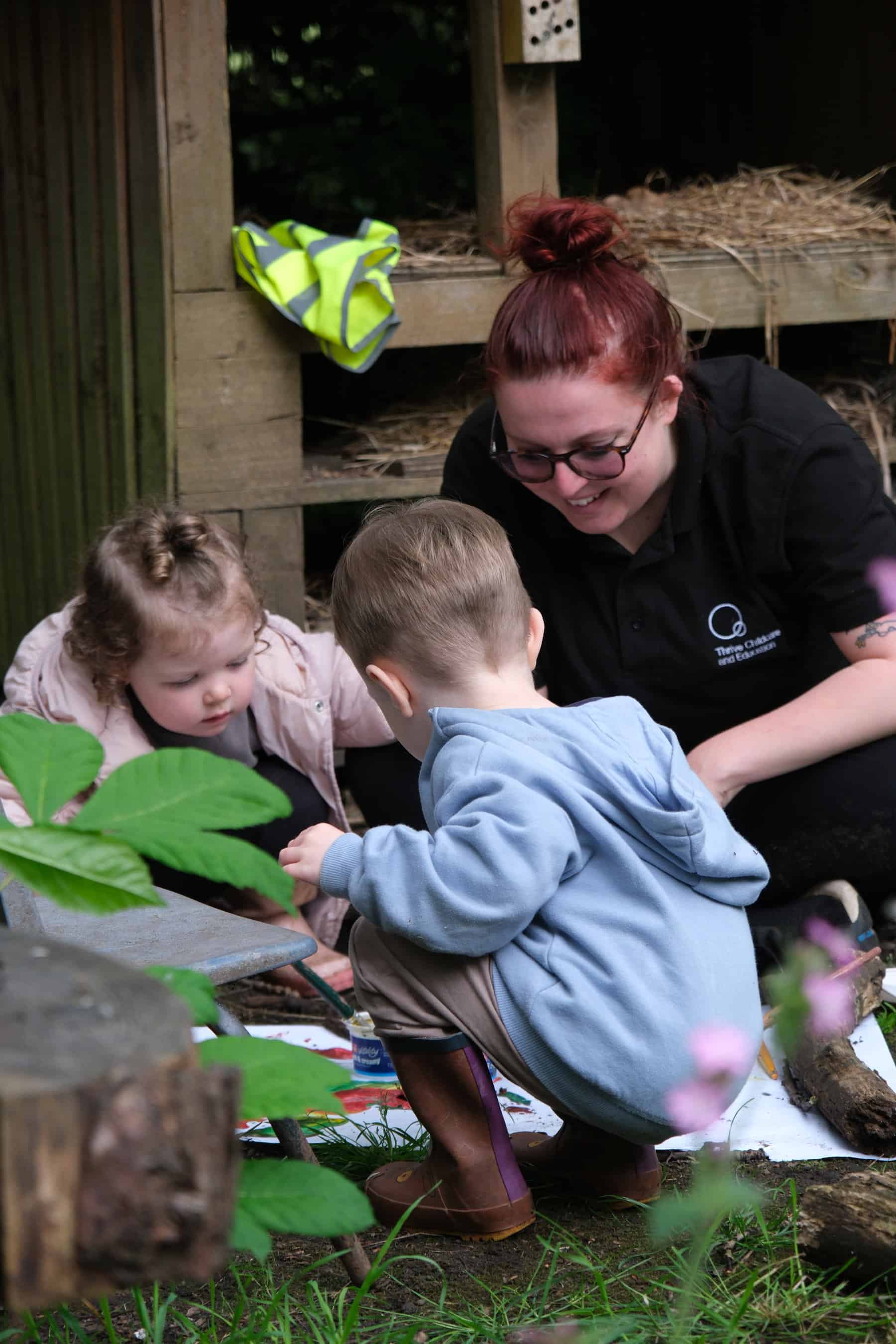 Young children engaging in outdoor activities with a caregiver at Thrive Childcare, promoting early childhood education, outdoor play, and development in a safe, caring environment.