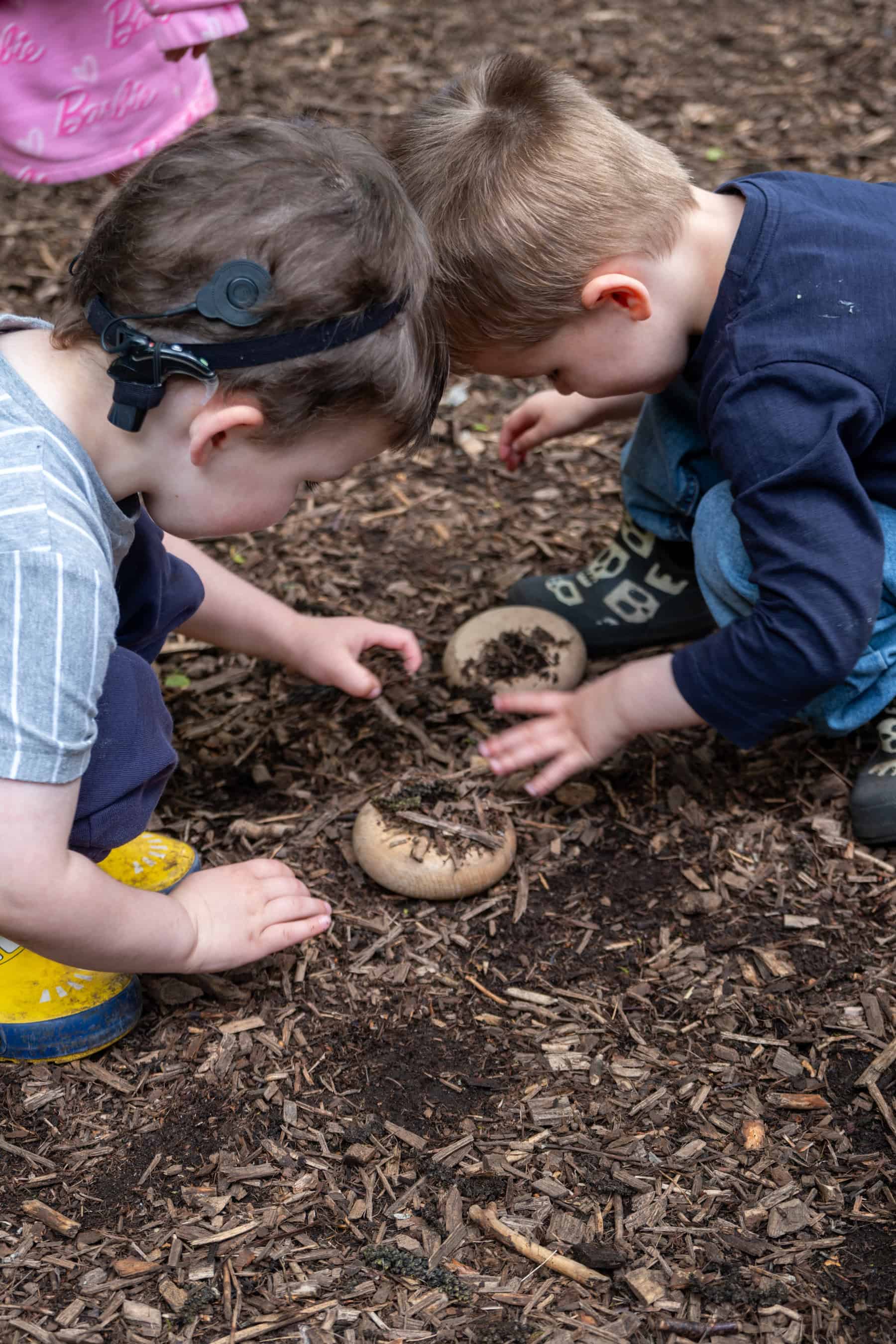 Young children exploring outdoors at Thrive Childcare, engaging in nature-based play and learning activities to promote development and curiosity.