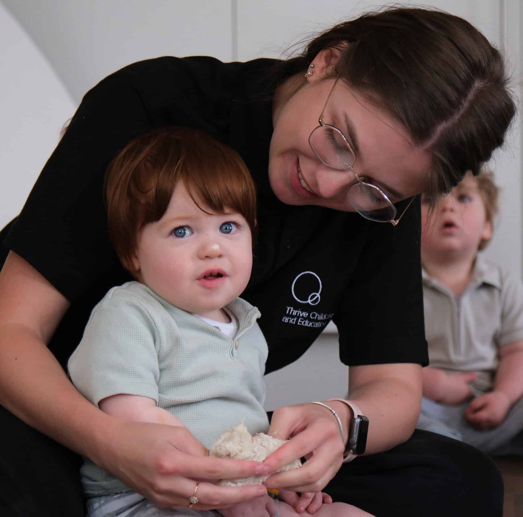 1. Caregiver engaging with young children in a nurturing childcare environment at Thrive Childcare.