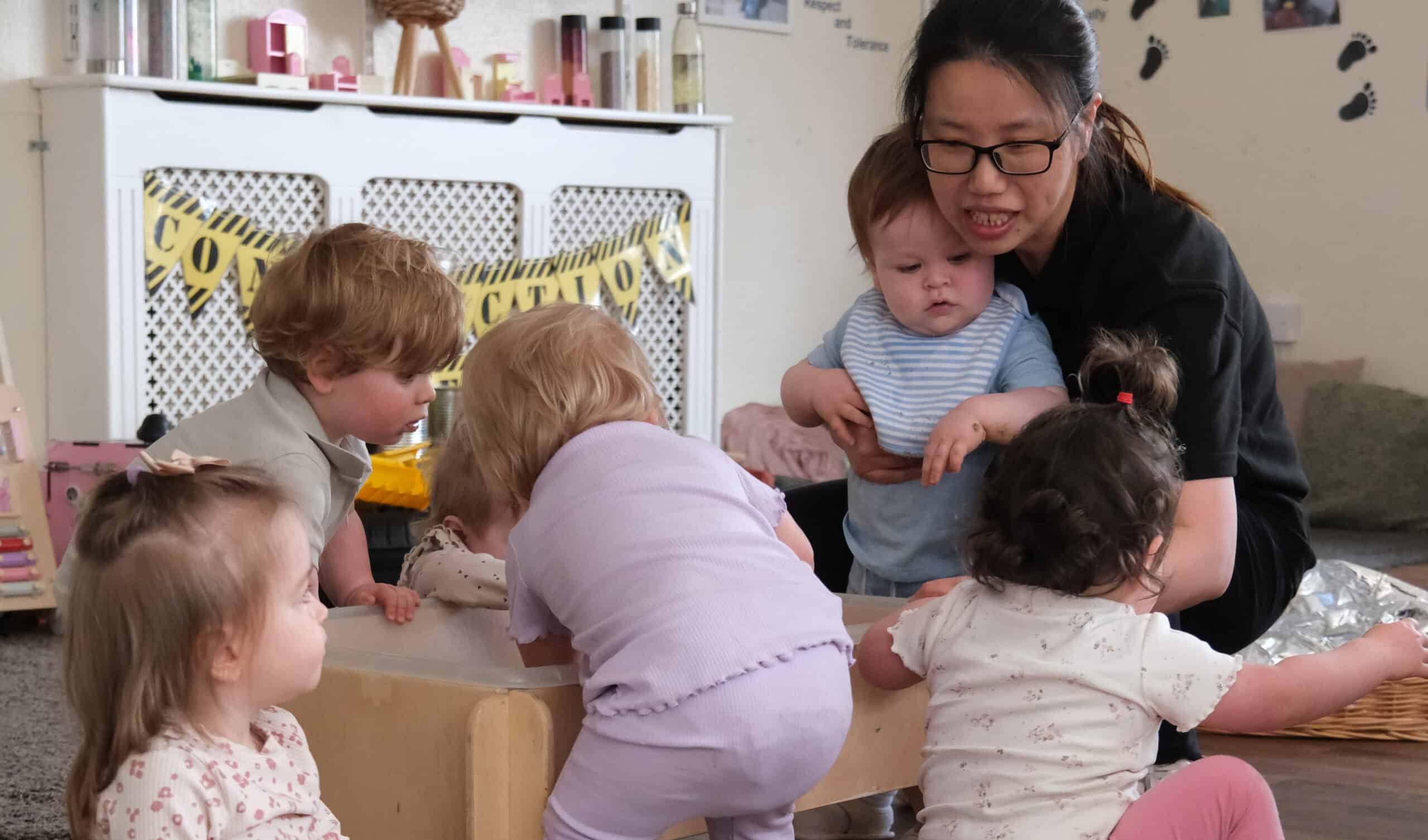 A vibrant childcare classroom at Thrive Childcare with diverse children engaged in learning activities, supported by a caring teacher, promoting early childhood development and nurturing environments.