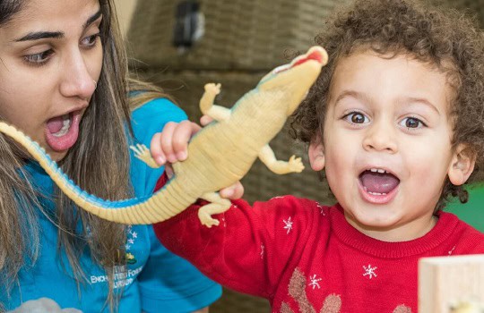 Bright young child playing with a toy crocodile during fun indoor activity at Thrive Childcare centre in the UK.