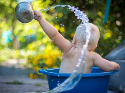 Young child playing with water outdoors at Thrive Childcare, summer fun, toddler activities, early childhood development, safe outdoor play space.