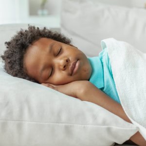 A happy child sleeping peacefully on a sofa, representing safe and nurturing childcare environment at Thrive Childcare.