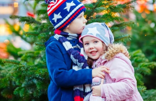 Brightly dressed children enjoying festive time at Thrive Childcare's holiday celebration with Christmas trees and holiday decorations.