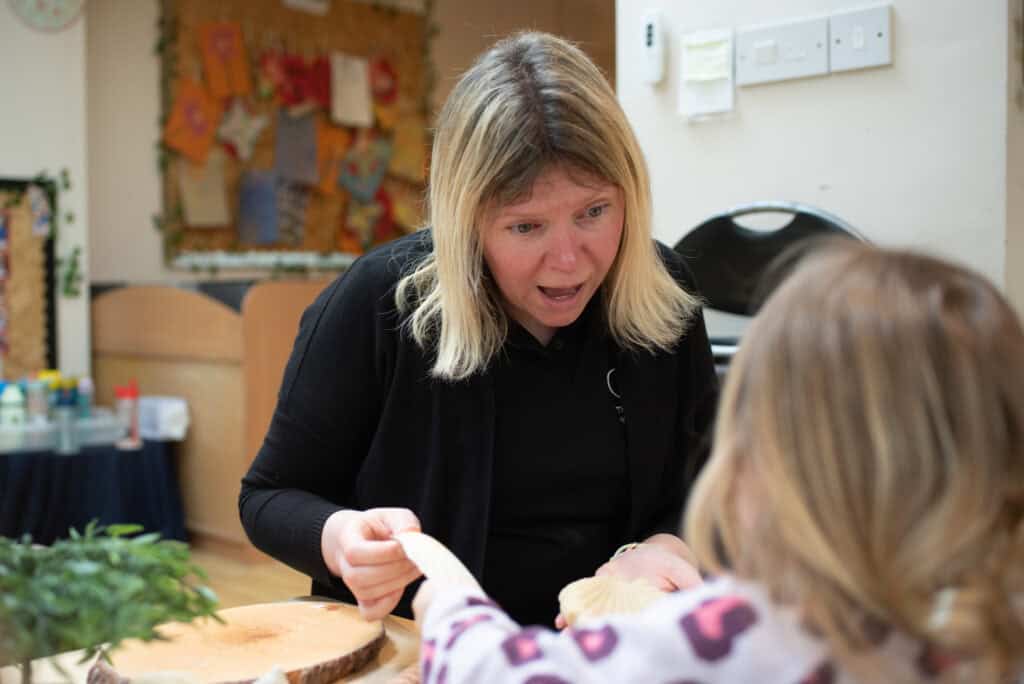 Engaging childcare provider interacting with a young girl, fostering developmental growth at Thrive Childcare. Focus on nurturing early childhood education and learning in a safe environment.