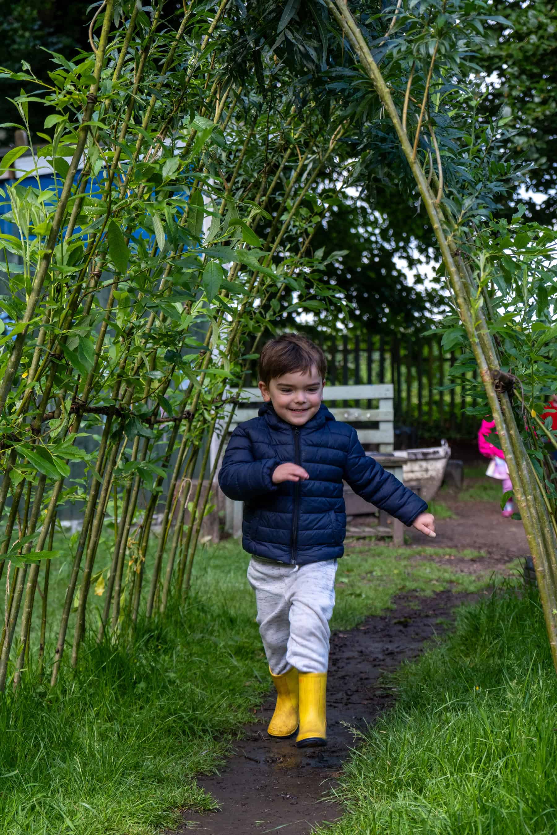 Young boy playing outdoors in a lush garden at Thrive Childcare, enjoying nature and outdoor activities with safe, engaging play areas for early childhood development.