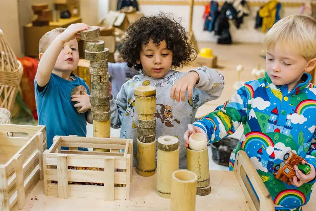 Colourful children playing with wooden blocks in a nursery classroom at Thrive Childcare, fostering early childhood development, creativity, and social skills.