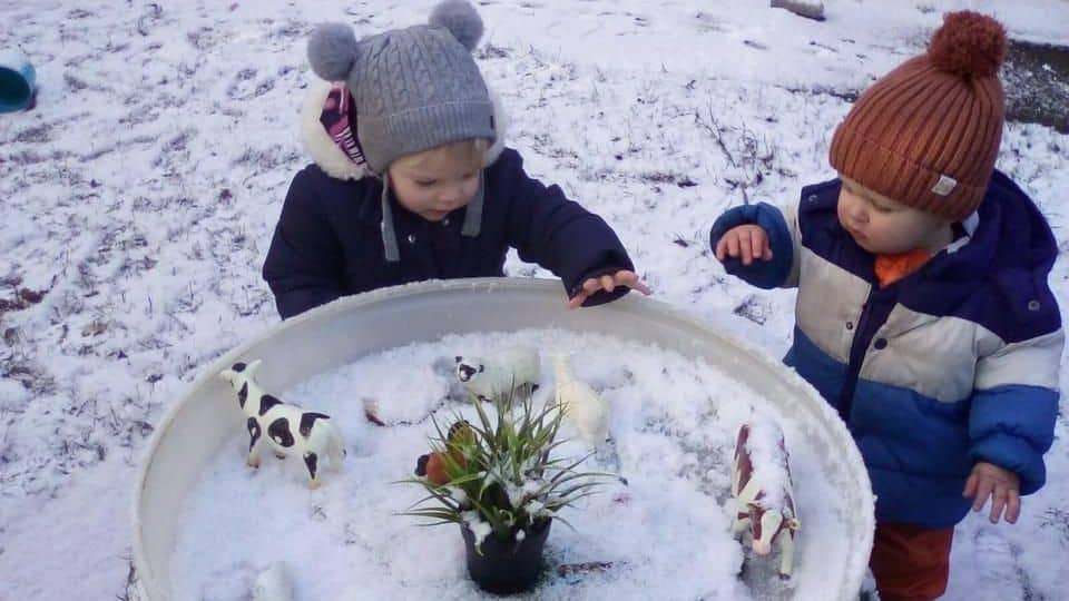 Children playing with miniature animals in the snow at Thrive Childcare, promoting outdoor activities, early childhood development, and nature exploration in a safe, nurturing environment.