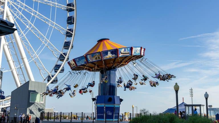 Children enjoying a swing ride at a colorful amusement park on a sunny day.
