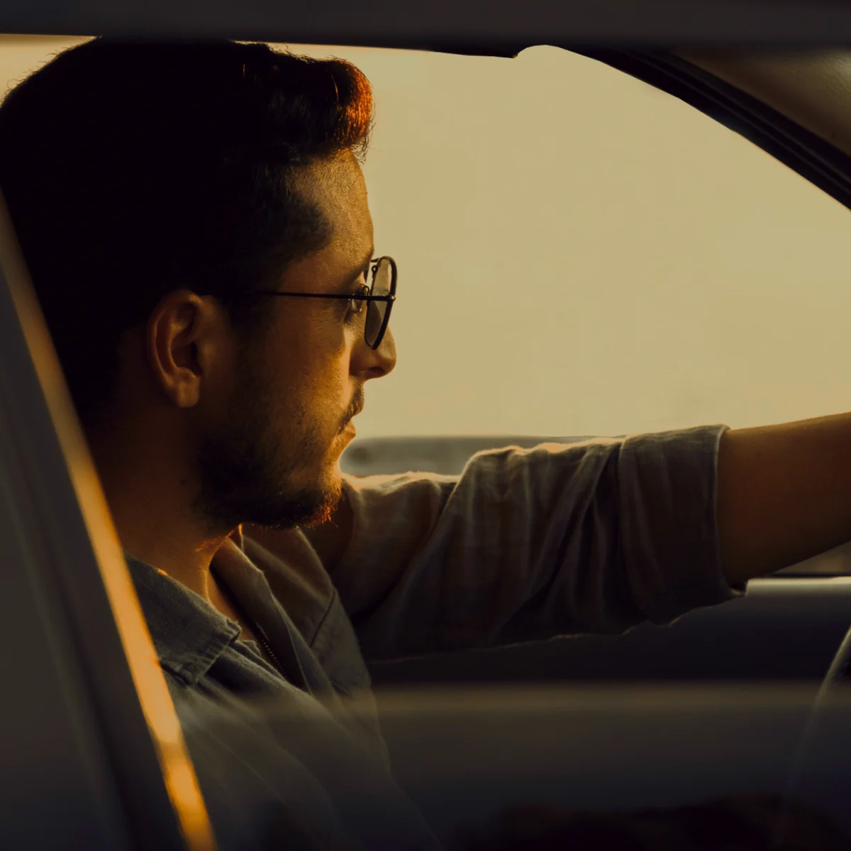 A man in glasses driving a car
