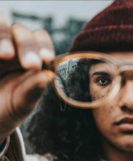 Notre plus.<br />
Gros plan du un verre de lunette tenu à bout de bras