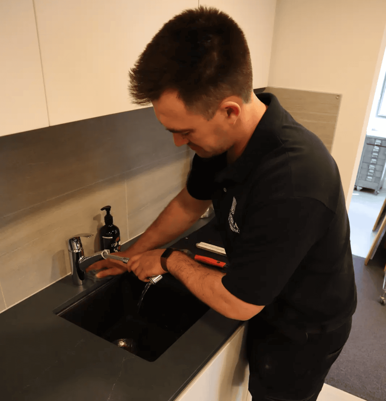 A plumber tests the water flow from a kitchen tap in a modern kitchen.