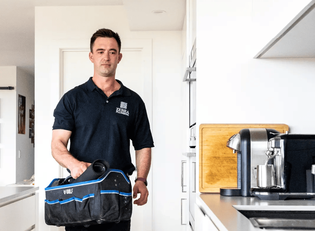 Zebra Plumbing technician arriving at a client’s home with equipment bag, ready for a scheduled plumbing service.