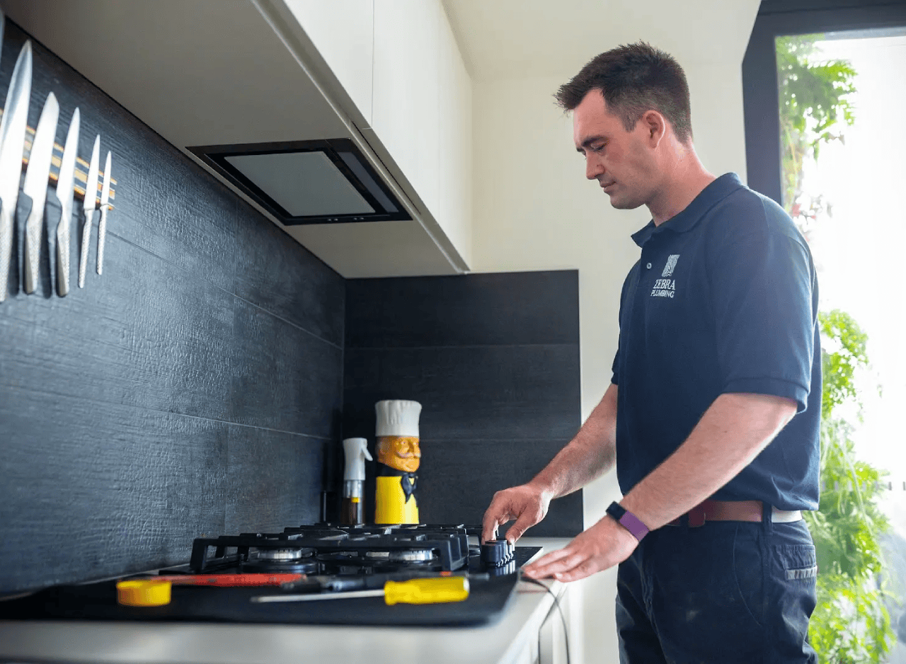 Zebra Plumbing technician testing a gas cooktop after completing a kitchen appliance installation.