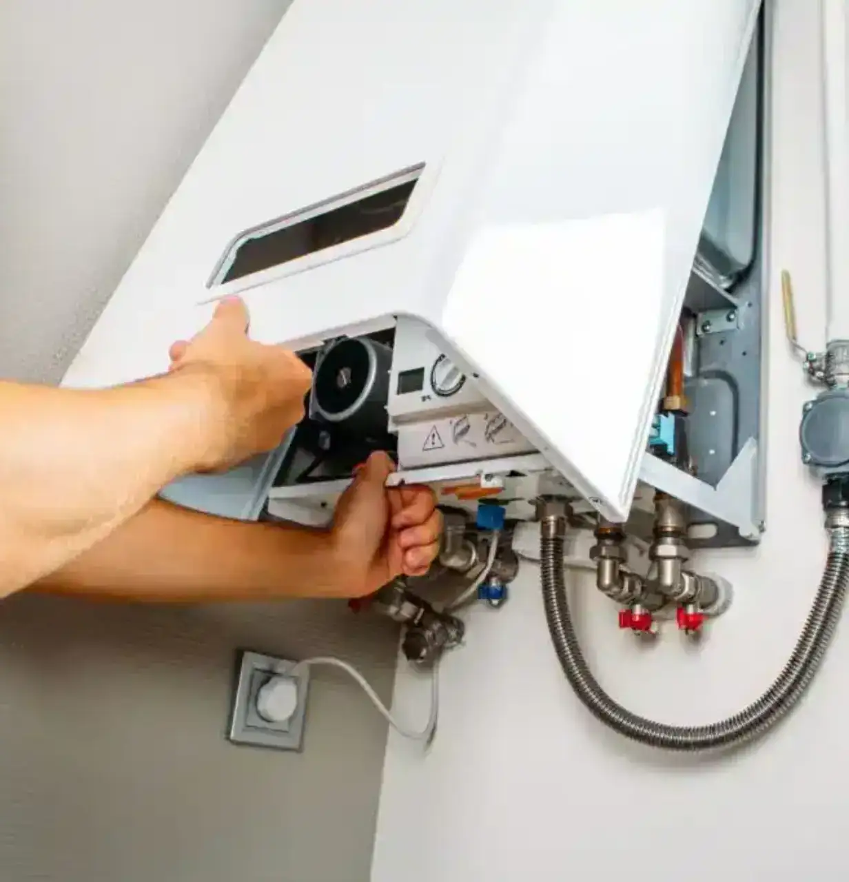 Technician repairing a hot water unit by accessing internal components.