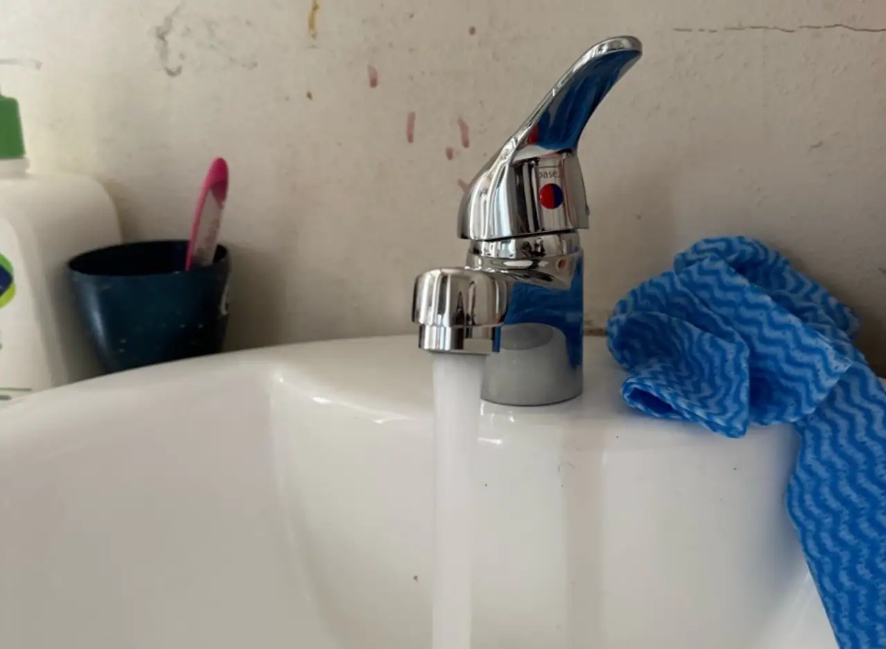 Kitchen sink with faucet and blue cleaning cloth for maintenance.