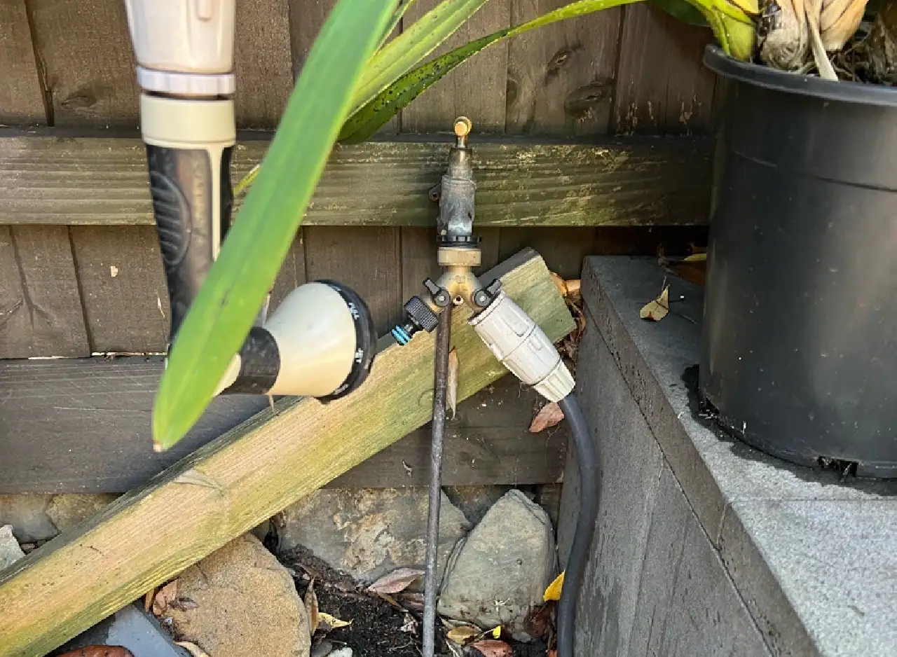 External drainage pipe repair with visible piping and garden setting.